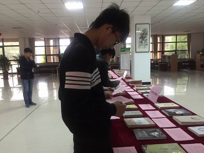 1524557144680461.jpg 读者驻足“优秀图书推荐”活动现场阅读图书3.jpg